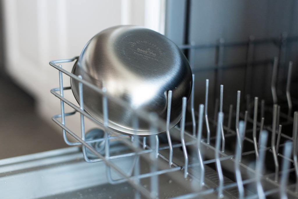 A stainless steel dog bowl in the bottom rack of a dishwasher.