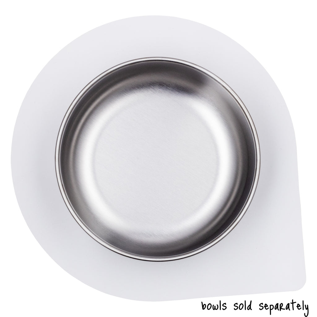 An empty, large size Basis Pet stainless steel dog bowl on a large size Ultra Grip mat shown from above. Text reads "bowls sold separately".