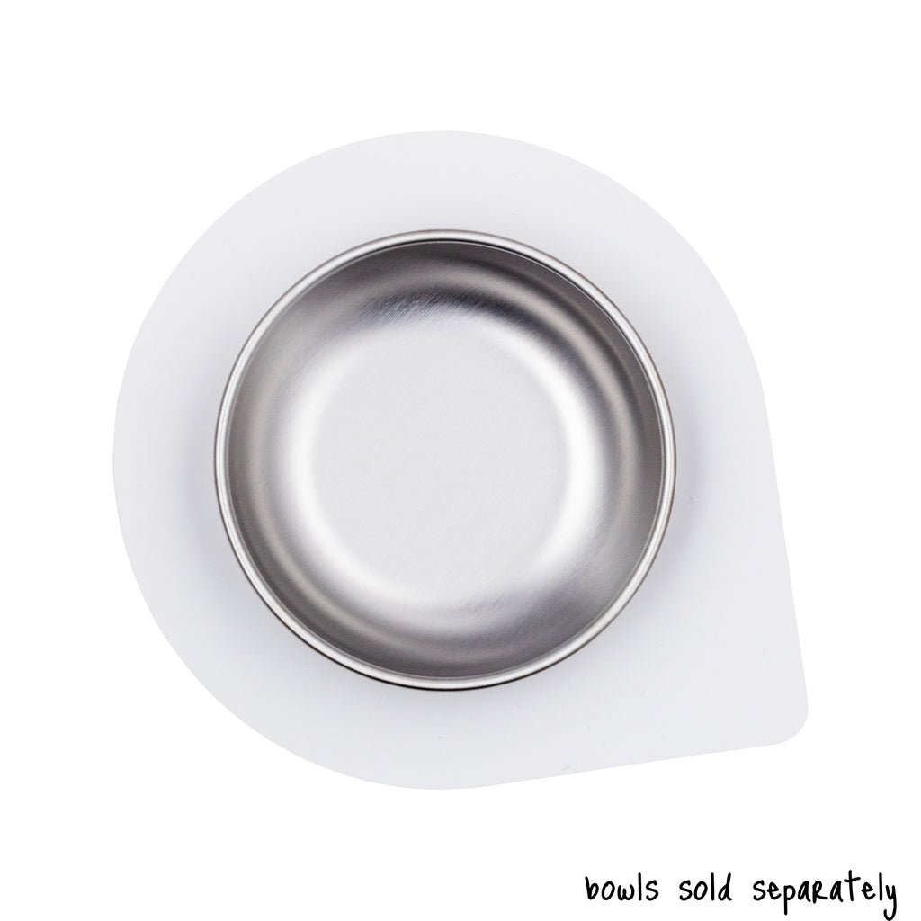 An empty, small size Basis Pet stainless steel dog bowl on a regular size Ultra Grip mat shown from above. Text reads "bowls sold separately".