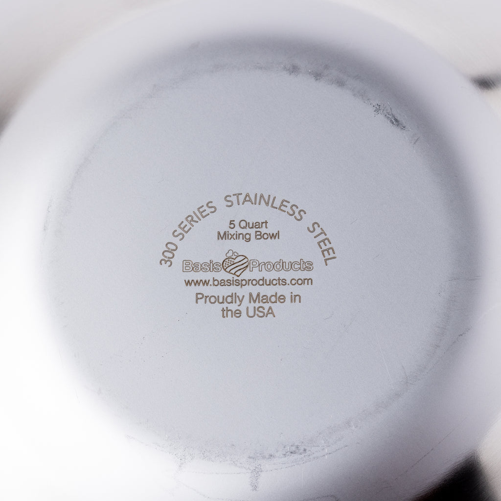 The bottom of a stainless steel mixing bowl which reads "300 Series Stainless Steel 5 Quart Mixing Bowl, Proudly Made in the USA by Basis Products"